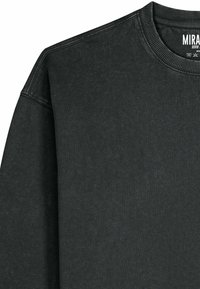 Felpa grigio scuro con scollo rotondo e polsini a costine. Realizzata in tessuto strutturato con un motivo sottile. Etichetta del marchio visibile.