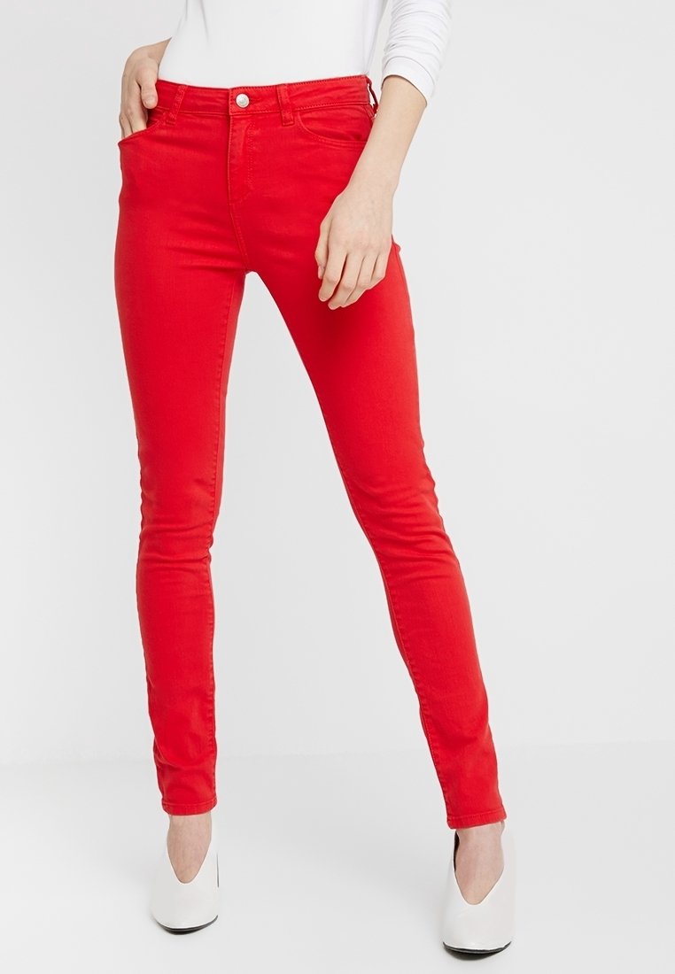 Jean skinny rouge en denim, avec une taille mid-rise, cinq poches et une fermeture à un bouton. Le tissu est lisse avec un léger éclat.