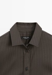 Camicia a righe marrone scuro con colletto classico, presenta quattro bottoni e un'etichetta con la scritta "Massimo Dutti". Tessuto morbido con una lieve lucentezza.