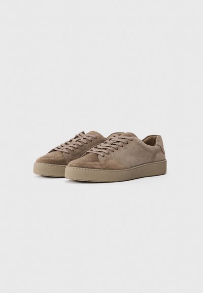 Pair of beige suede low-top sneakers with matching laces and rubber soles on a plain light background.