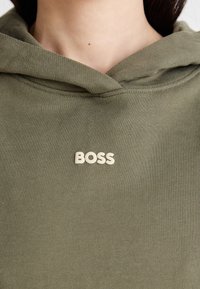 Felpa verde oliva realizzata in morbido cotone, con un logo bianco "BOSS" ben in evidenza sul petto e una vestibilità comoda con cappuccio.