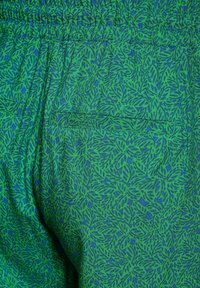Gröna tygshorts med ett bladmönster i olika nyanser av grönt och blått. Elastisk midja med en bakkert detalj.