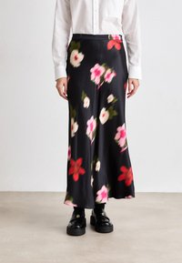 Blomstrete midi-skjørt i svart sateng med rosa og røde blomster. Har høyt liv og glatt tekstur, kombinert med svarte loafers.
