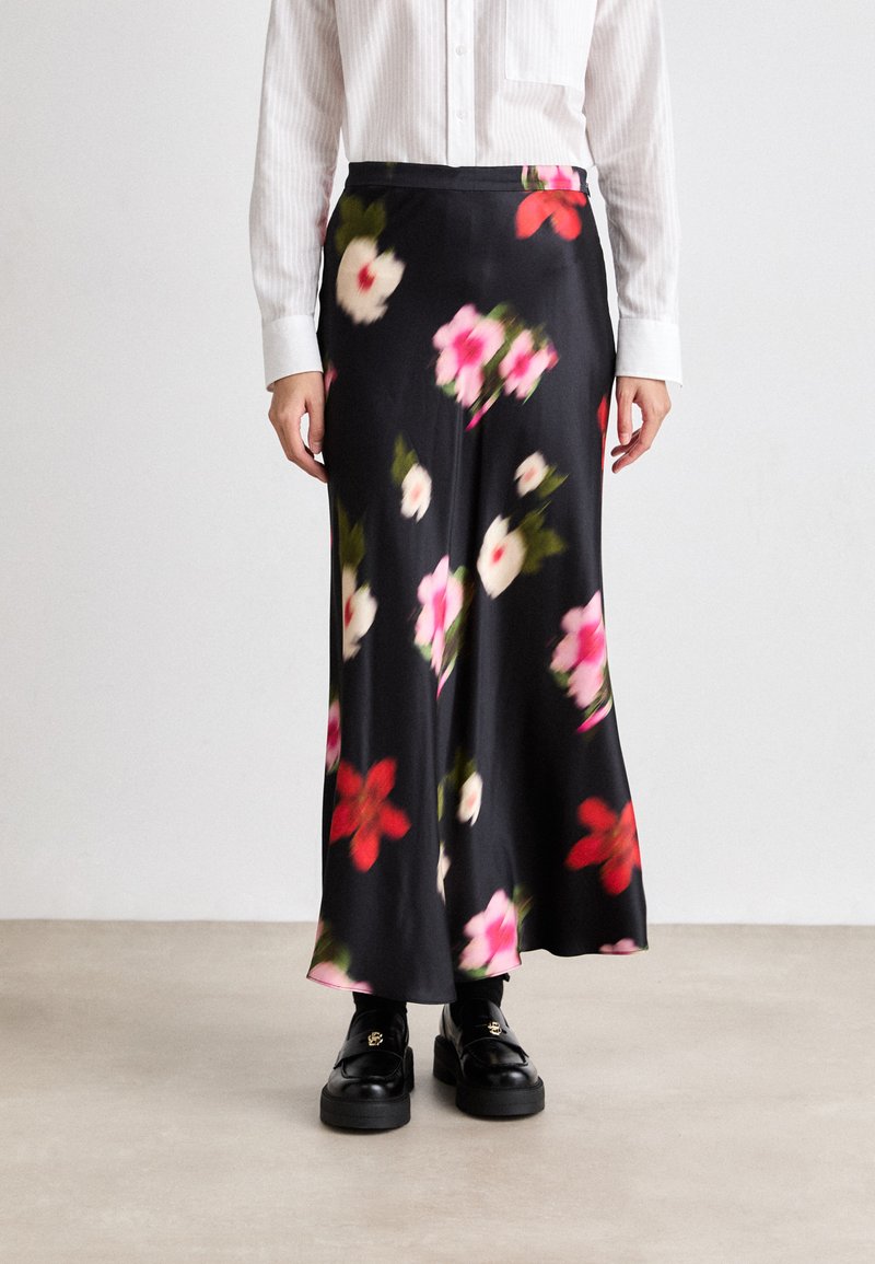 Blomstrete midi-skjørt i svart sateng med rosa og røde blomster. Har høyt liv og glatt tekstur, kombinert med svarte loafers.