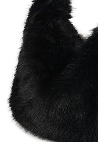 Tissu en fausse fourrure noire douce avec des fibres denses et brillantes formant une surface moelleuse et courbée sur fond blanc.