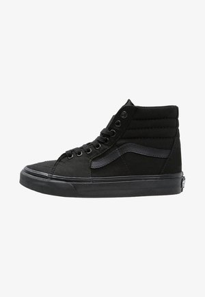 Czarny sneaker za kostkę z wyściełanym kołnierzem, czarne sznurówki, charakterystyczny boczny pasek i gruba gumowa podeszwa.