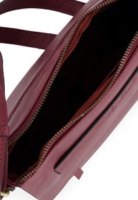 Rød lædertaske med lynlåslukning og indvendig stofforing. Har diagonale stropper og rektangulær form.