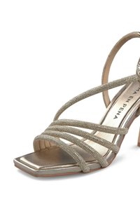 Metallisch goldener High-Heel-Sandalette mit mehreren schlanken Riemen, die mit kleinen Edelsteinen verziert sind, quadratischer offener Zehenbereich und Blockabsatz.