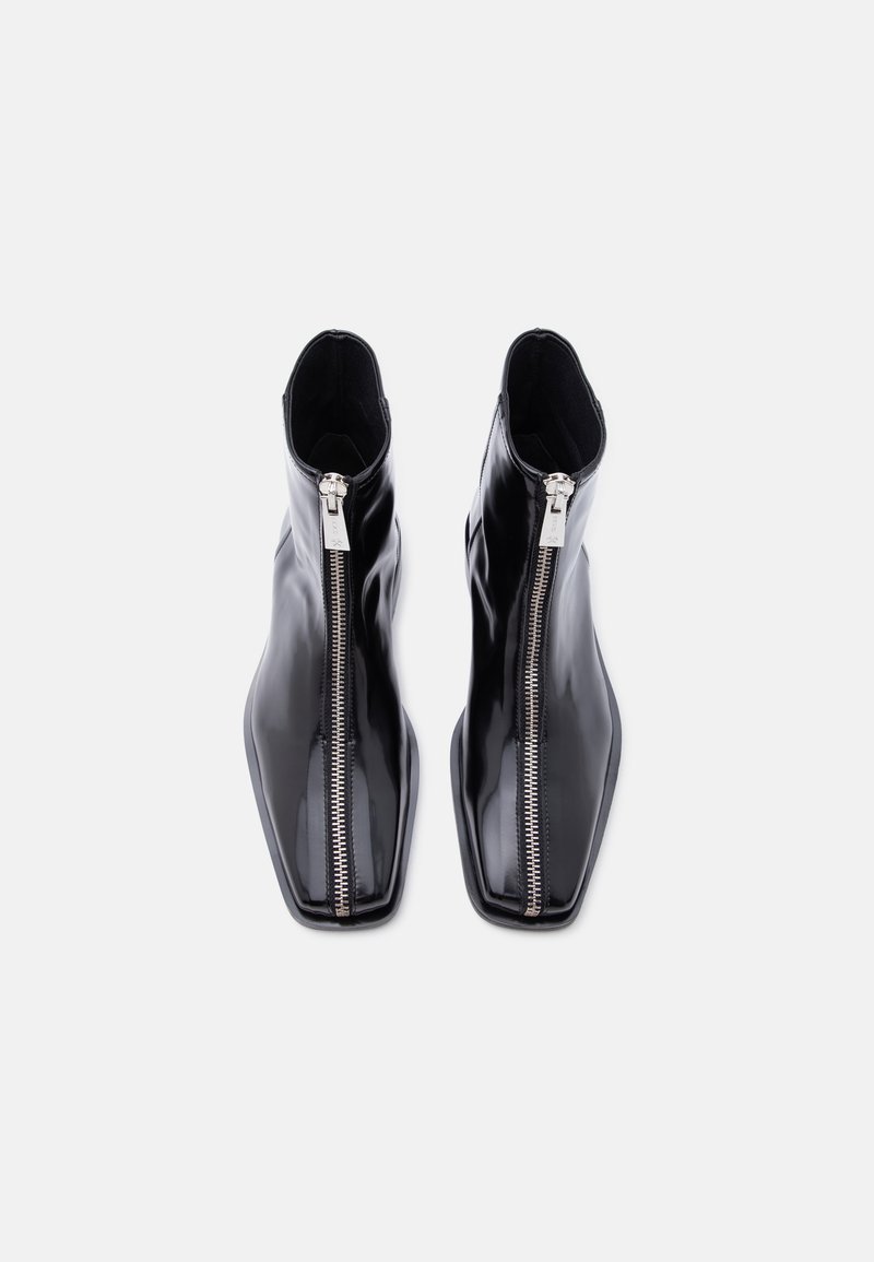 Pair of black glossy leather ankle boots with front silver zippers and square toes on a white background.