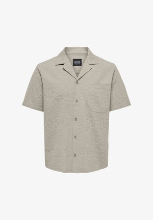 Kortermet skjorte med knapper i lys beige med teksturert stoff, lomme, og krage. Har fem knapper foran.