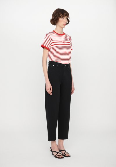 Red and white striped t-shirt with short sleeves, paired with high-waisted black denim pants. Black strappy sandals complete the outfit.