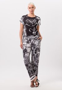 Zwart-witte set van een bloemetjespatroon top en broek. De top heeft korte mouwen; de broek heeft zijzakken en een relaxte pasvorm. Soepele textuur.