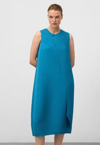 Ein ärmelloses, türkisfarbenes Kleid mit horizontalen Falten, das eine diagonale Naht und einen einzelnen Knopfverschluss aufweist. Es hat eine lockere Passform, die unter das Knie fällt.