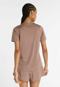 Brown athletic t-shirt with a textured fabric, short sleeves, and raglan seams, paired with matching shorts. Seen from the back.