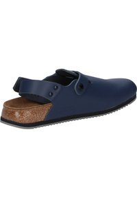 Navyblaue Slipper mit Korkfußbett, weichem Obermaterial, verstellbarem Riemen und strukturierter Gummisohle. Mit dezenten Hardware-Elementen und ohne Absatz.