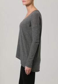 Haut gris à manches longues avec un col en V et une texture côtelée sur les manches. Coupe décontractée, ourlet droit et tissu doux.