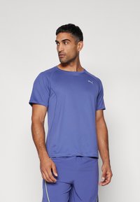 T-shirt atlético roxo com decote redondo, mangas curtas e um discreto destaque de logo, combinado com calções a condizer para um look completo.
