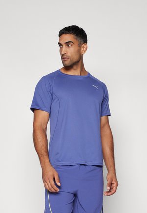 Camiseta deportiva púrpura con cuello redondo, mangas cortas y un sutil acento de logo, combinada con pantalones cortos a juego para un look completo.