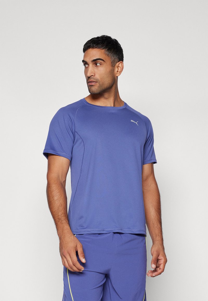 T-shirt atlético roxo com decote redondo, mangas curtas e um discreto destaque de logo, combinado com calções a condizer para um look completo.