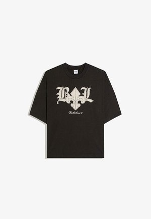 Crna majica kratkih rukava s velikim bež motivom fleur-de-lis i gotičkim slovima "BL" iznad riječi "Brotherhood 9" sprijeda.