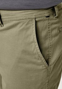 Olivgrüne Baumwollchinos mit flachem Front, Seitentaschen und strukturierter Oberfläche im Straight-Leg-Design.