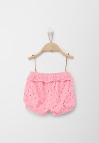 Shorts en coton rose avec une taille froncée, présentant des détails en broderie anglaise et un élastique au niveau des jambes, suspendus sur un cintre en bois contre un fond blanc.