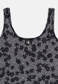 Μαύρο και λευκό ριγέ τοπ με λεπτές τιράντες και μια μικρή μαύρη ετικέτα με λευκή επιγραφή "cK" στο ντεκολτέ.