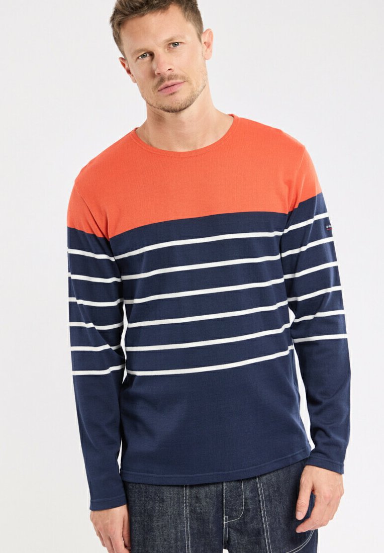 Chemise à manches longues avec une partie supérieure orange et un corps bleu marine avec des rayures blanches horizontales. Fabriquée en tissu doux et texturé.