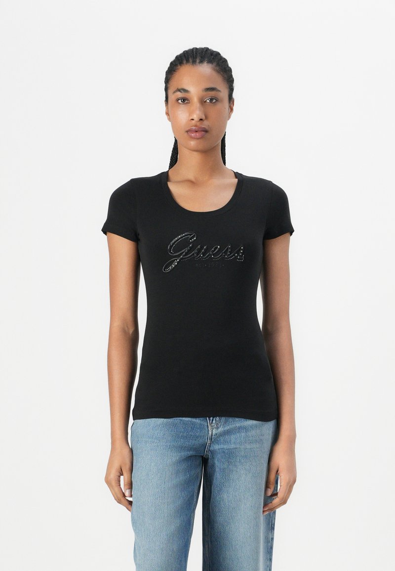 Black fitted t-shirt with short sleeves, featuring a ribbed scoop neckline and sparkling "Guess" logo detail on the front.