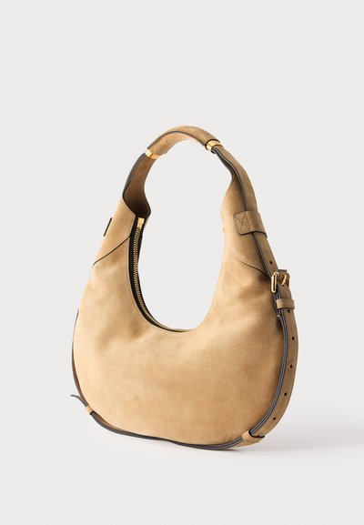 Sac à main en daim couleur tabac en forme de croissant avec fermeture éclair dorée, bandoulière réglable et bordure foncée sur un fond clair uni.