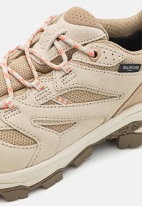Beige tursko med nubuck- og mesh-øvre, teksturert design, kontrasterende oransje snøring og robust gummisåle for godt grep.