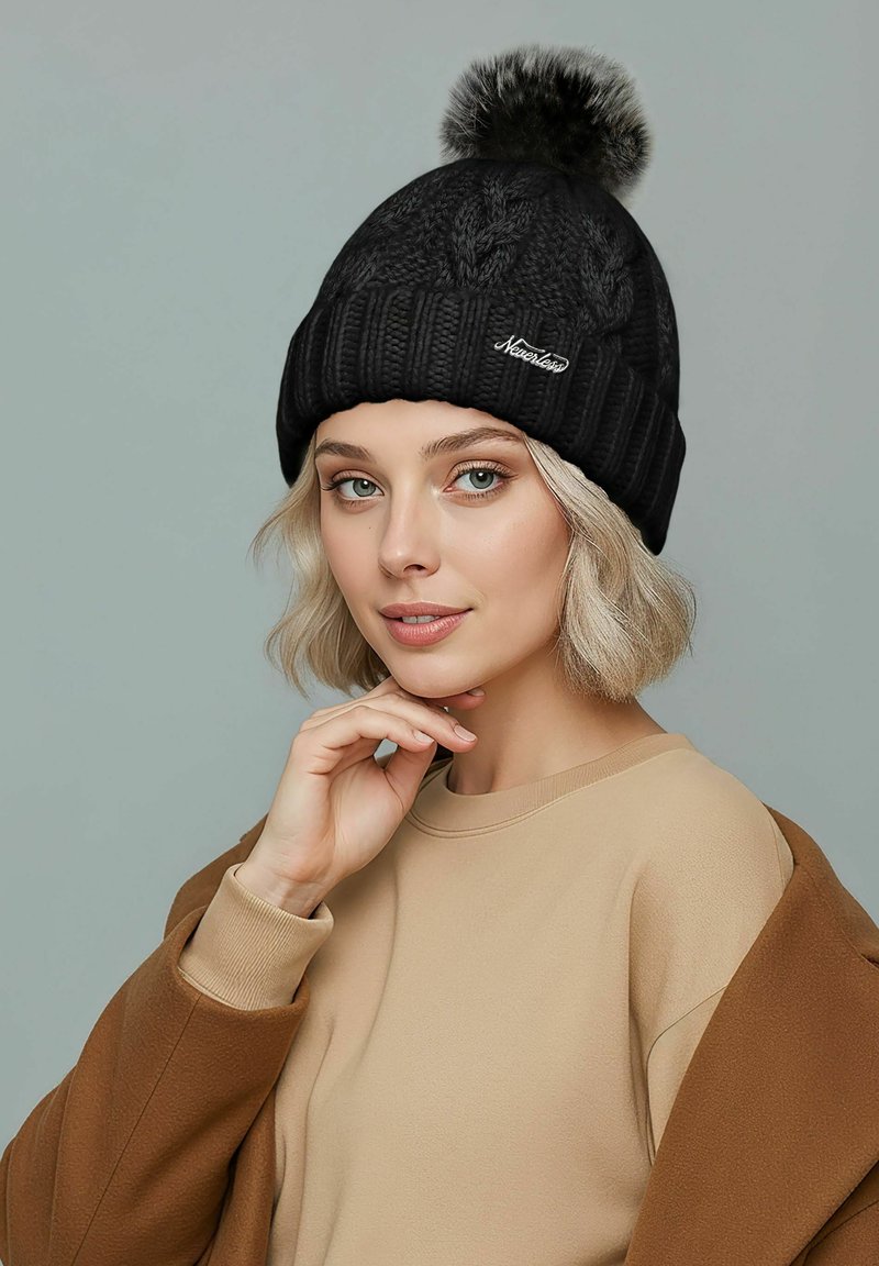 Black knitted beanie with a textured pattern, featuring a fur pom-pom on top and a ribbed cuff. Includes a small embroidered logo.