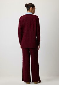 Bordo kootud särk ja vastavad püksid, laiad sääred ja soonikkoes äärised. Pehme tekstuur, lõdva istuvusega ja kraedetailidega.