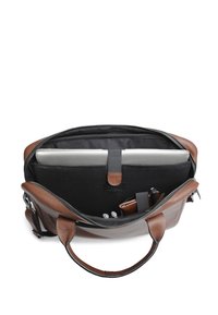 Sac à dos en cuir marron avec une ouverture zip, featuring un intérieur noir, des compartiments pour un ordinateur portable, des stylos et un portefeuille. Texture lisse.
