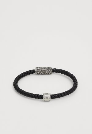 Zwart gevlochten leren armband met twee zilveren decoratieve sluitingen met sierlijke gravures.