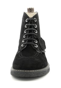 Botines de ante negros que cuentan con cordones redondos, un acento circular en el lateral y una suela de goma texturizada con costuras.