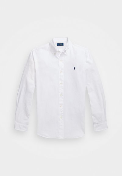 Camisa branca com botões, de mangas longas, colarinho, apresentando um pequeno logótipo azul-marinho no peito, feita de algodão com uma textura suave.