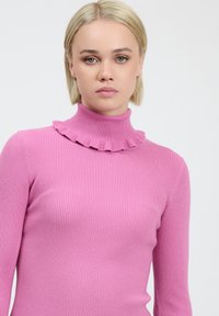 Engentliches Turtleneck-Pullover aus leuchtend pinkfarbenem Rippstoff, mit einem gerafften Kragen und langen Ärmeln, in einer glatten, matten Textur.