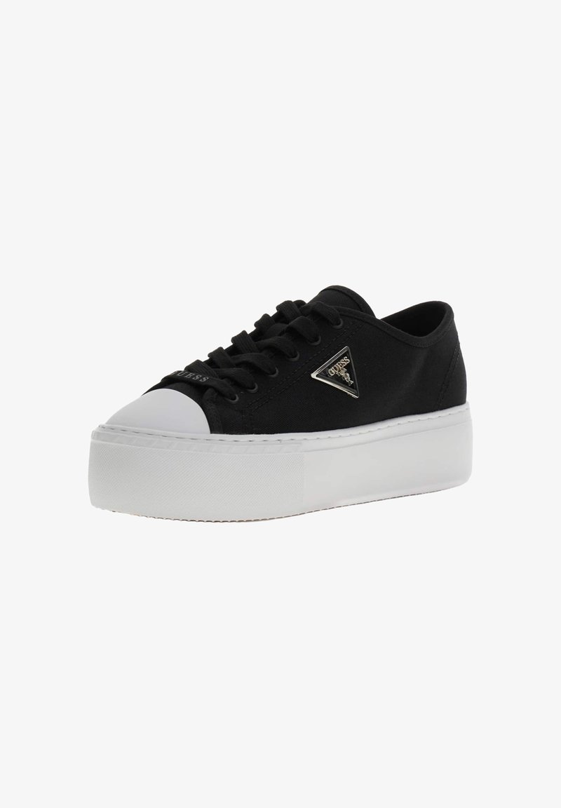 Baskets basses noires avec semelle plateforme blanche, protection blanche au niveau des orteils, lacets noirs et logo métallique triangulaire Guess sur le côté.
