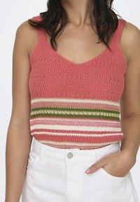 Dziergany top na ramiączkach z różową górną częścią i poziomymi paskami w kolorze kremowym, zielonym i ciemniejszym różowym. Dekolt w kształcie litery V, lekka faktura.