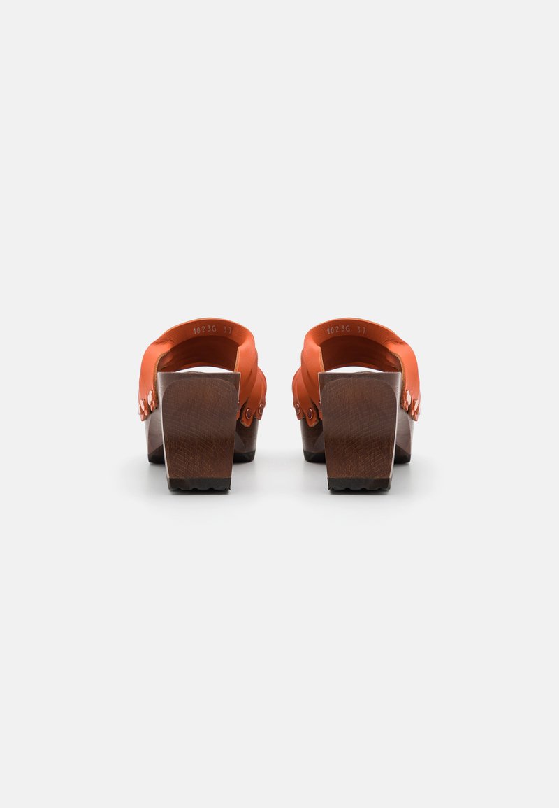 Orange Slide-Sandalen mit einem breiten Riemen, Holz-Blockabsatz und strukturiertem Sohle. Detail der Hardware am Riemen von hinten sichtbar.