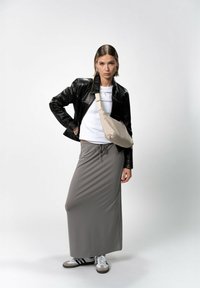 Giacca di pelle nera, t-shirt bianca, gonna lunga grigia, borsa a tracolla beige e sneakers bianco e nere; texture morbide e design casual.