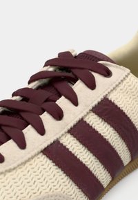 Sneaker in pizzo bordeaux con tomaia in rete e suede avorio, caratterizzate da tre strisce bordeaux e suola in gomma testurizzata.