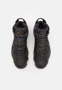 Chaussures de sport montantes noires avec une tige en cuir lisse, des accents gris, une doublure en mesh et un logo rond sur la languette. Dotées de lacets et de languettes pour faciliter l'enfilage.