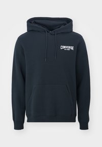 Sudadera azul marino con capucha, bolsillo frontal, puños acanalados y cinturilla. Presenta el logo blanco de "Converse All-Star" en el pecho.
