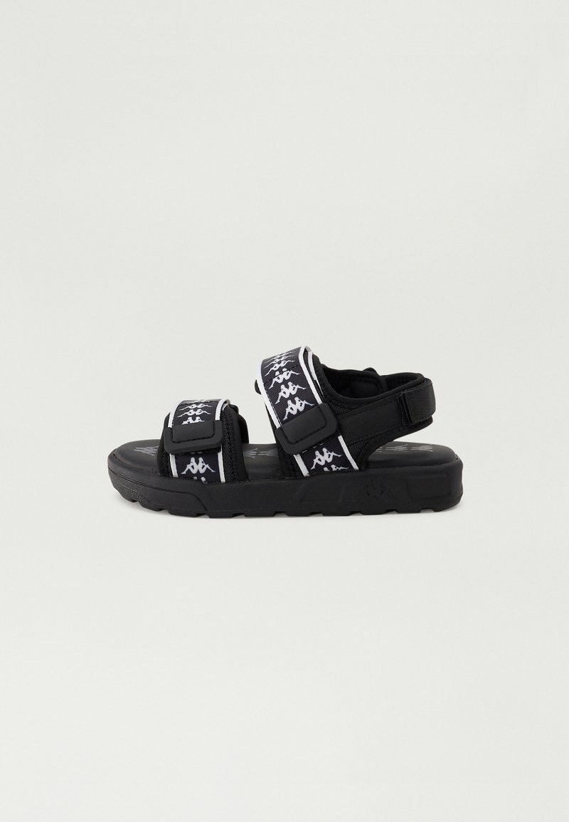 Sorte sandaler med justerbare stropper og et hvitt logomønster, teksturert såle og en polstret fotseng for komfort.