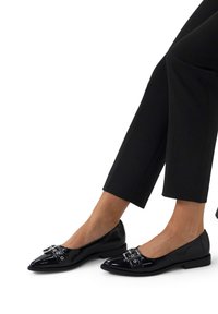 Zwarte lakleren ballerina's met een spits toe, decoratieve zilveren gespdetail op de voet en lage platte hak.