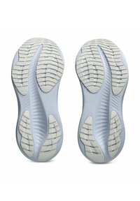 Semelles de chaussures de sport grises et blanches, montrant des motifs de semelle texturée conçus pour l'adhérence et la flexibilité.