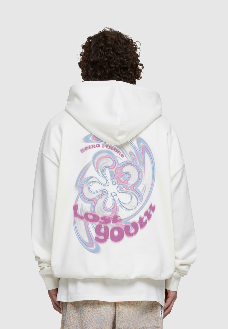 Vit oversized hoodie med en mångfärgad virvelgrafik och texten "Lost Youth" i rosa på baksidan. Blandning av bomull.