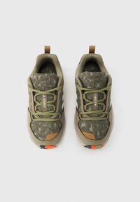 Αθλητικά παπούτσια σε ελιά πράσινο με υφή καμουφλάζ, επάνω μέρος από δ ίχτυ και μπεζ λεπτομέρειες. Διαθέτουν λαστιχένια σόλα με φωτεινές πορτοκαλί λεπτομέρειες.